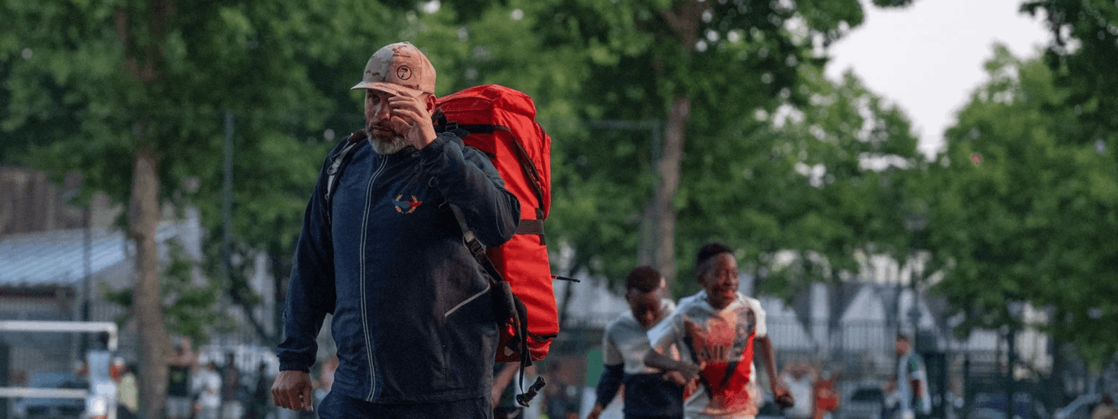 Encadrant Mission Alpha sac au dos supervisant un événement sportif en plein air avec des jeunes