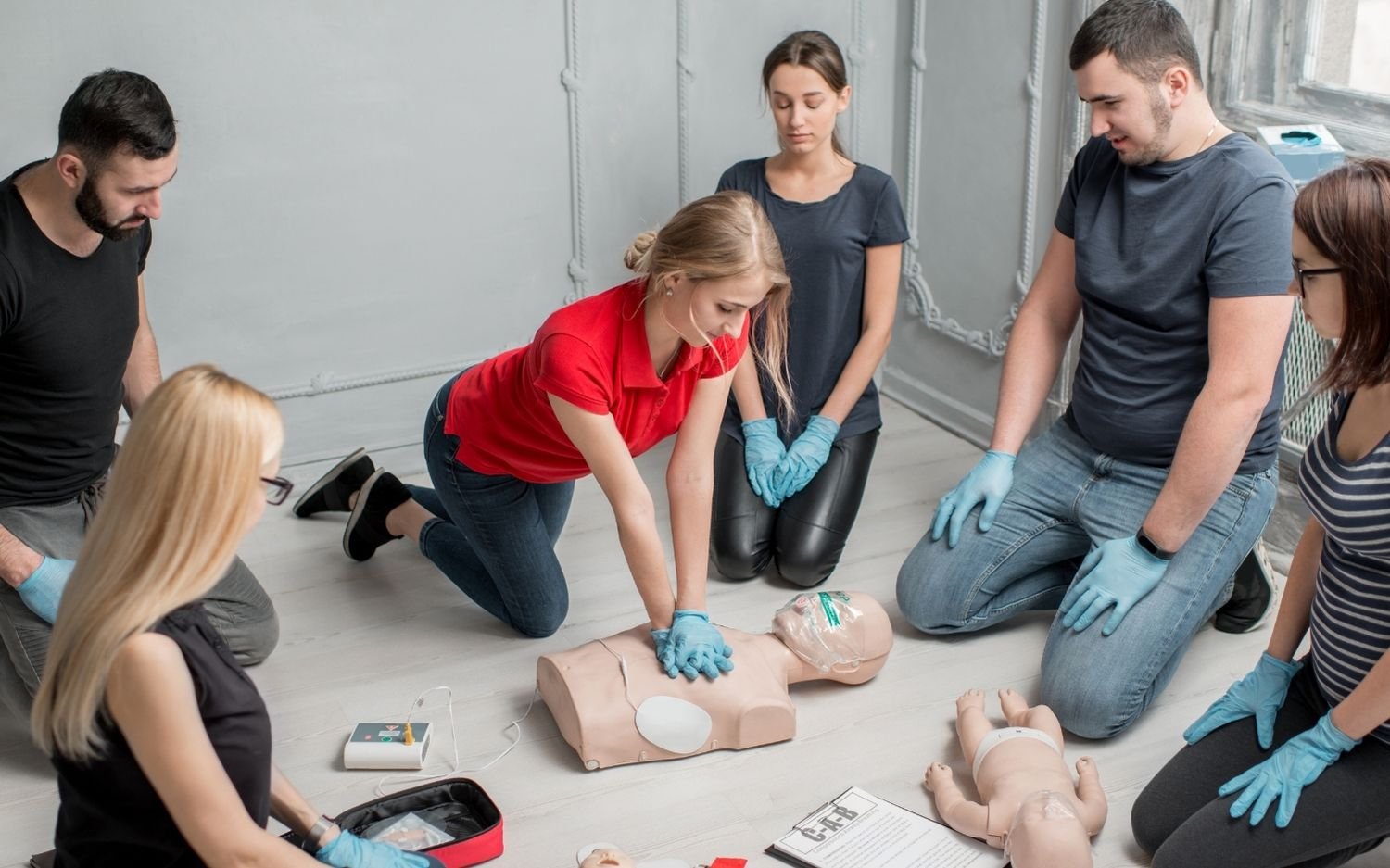 Groupe en formation aux premiers secours pratiquant un massage cardiaque sur mannequin d'exercice