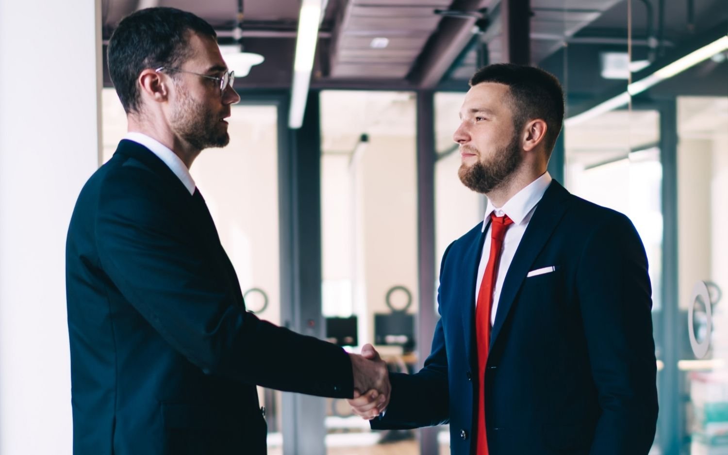 Poignée de main entre deux hommes en costume, symbole d'une réinsertion professionnelle réussie